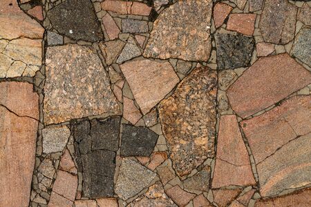 The texture of the sidewalk of chaotic granite stones of different colors with many cracksの写真素材