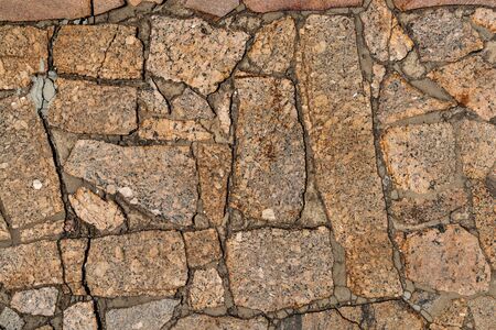 The texture of the sidewalk of chaotic granite stones of different colors with many cracksの写真素材