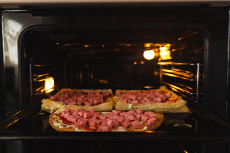 Homemade pizza in the oven close-up, sausage sprinkled with cheese