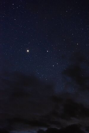 Stars in the night sky through the cloudsの写真素材