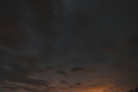 Stars in the night sky through the clouds on a summer nightの写真素材