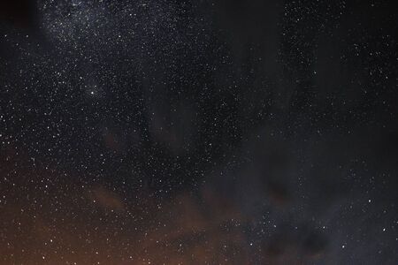Stars in the night sky through the clouds on a summer nightの写真素材