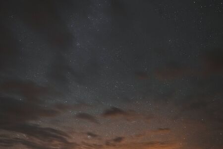 Stars in the night sky through the clouds on a summer nightの写真素材