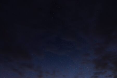 Stars in the night sky through the clouds on a summer nightの写真素材