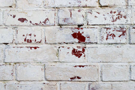 The texture of the old brick wall painted white with peeling paintの写真素材