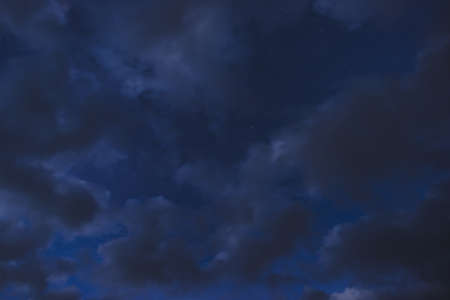 Stars in the night sky through the clouds on a summer nightの写真素材