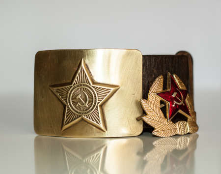 Old soviet soldier's belt with brass buckle and cap badge with a starの写真素材