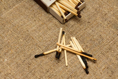 A handful of burnt matches and matchbox on rough canvasの写真素材