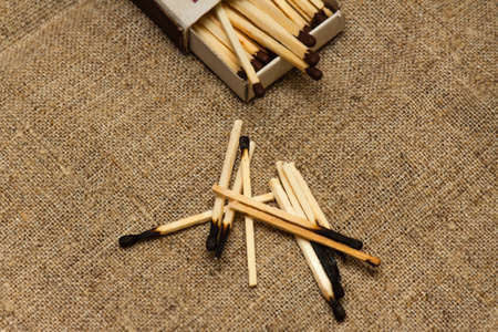 A handful of burnt matches and matchbox on rough canvasの写真素材