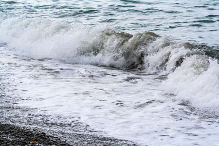 Turbulent sea waves roll on the shore of pebblesの写真素材