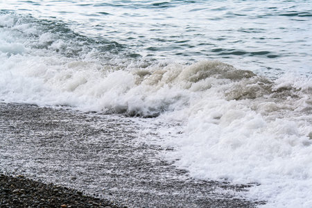 Turbulent sea waves roll on the shore of pebblesの写真素材