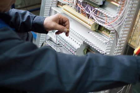 Electrician assembling industrial control cabinet in workshop. Close-up photo.