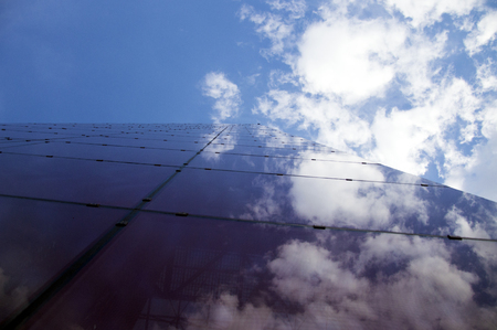 Perspective view of the modern building facade with clouds reflections on the windows glassの写真素材
