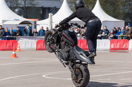 MINSK, BELARUS - APRIL 24, 2016 HOG. Harley Owners Group opening driving season show. Man stunt riding with black Harley Davidson sports bike.のeditorial素材
