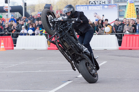 MINSK, BELARUS - APRIL 24, 2016 HOG. Harley Owners Group opening driving season show. People watching the man doing extreme trick with black Harley Davidson motor bike.のeditorial素材