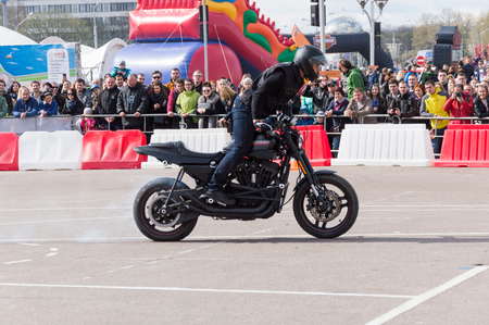 MINSK, BELARUS - APRIL 24, 2016 HOG. Harley Owners Group opening driving season show. People watching the man doing extreme tricks with black Harley Davidson motor bike.のeditorial素材