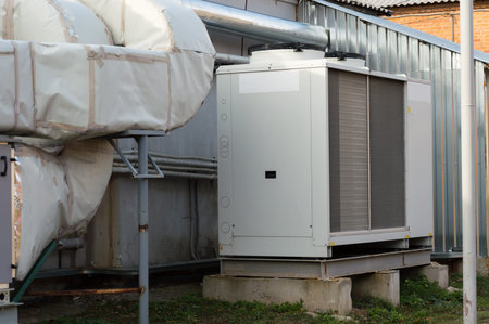Gray cooling unit for central ventilation system with big ventilation unit standing outdoor on the...