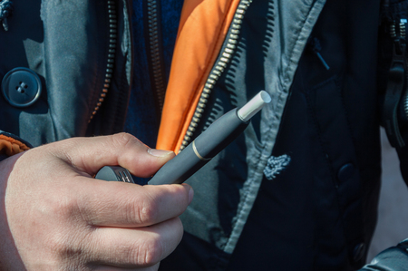 A heat-not-burn tobacco product technology.Man holding in one hand smoking module before smoking.の写真素材