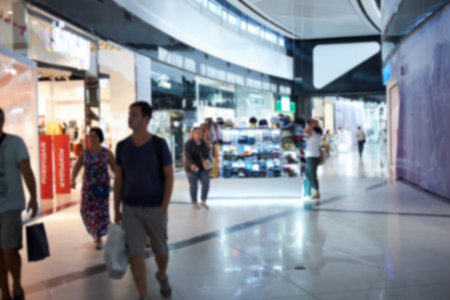 Blurred photo of the people walking inside the light and modern shopping mall centre. Can be used...