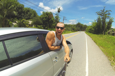 Young Happy Man Taking Selfie Picture with Smartphone on Monopod Stick. Hipster Making Road Trip...