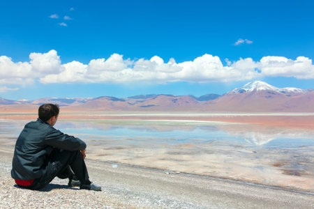 Young man sitting alone on the shore of Laguna Colorada, Bolivia