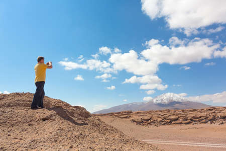 Man taking pictures of snowy mountain at Bolivian altiplanoの写真素材