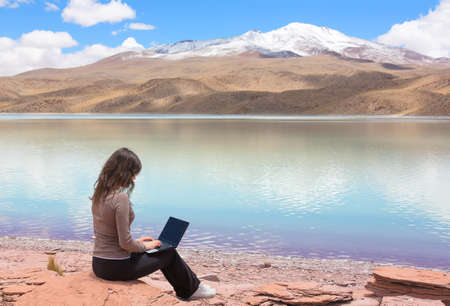 Woman with laptop on the shore of mountain lake Laguna Celeste, Boliviaの写真素材