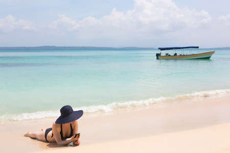 Woman looking at mobile phone on the beachの写真素材