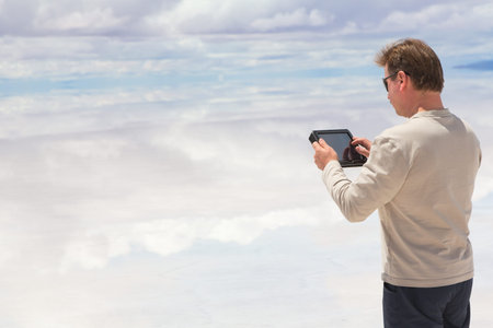 Man working on digital tablet in the middle of lake Salar de Uyuini, Bolivia