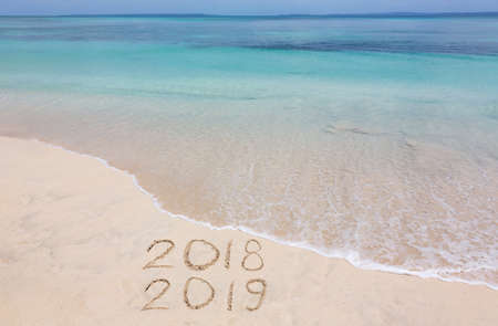 Years 2018 and 2019 are inscribed on sandy beachの写真素材