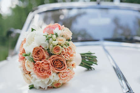 Wedding bouquet on the hood of a white retro carの写真素材