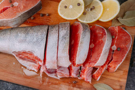 slices of raw salmon on a wooden board with lemon pepper and bay leafの写真素材