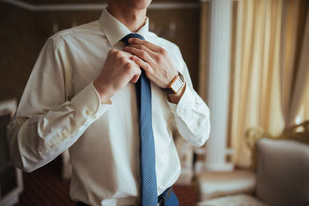 The groom adjusts his tie. Wedding preparationの写真素材