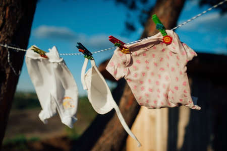 baby clothes drying on a rope in the woodsの写真素材