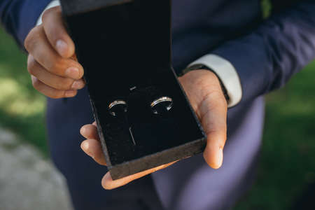 Groom holding two wedding rings on his hand close upの写真素材