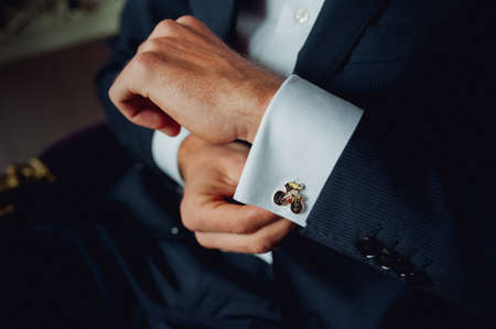 Groom buttoning a shirt on a white weddingの写真素材