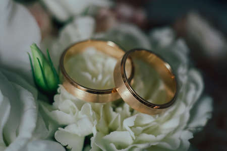gold wedding rings on a white flowerの写真素材