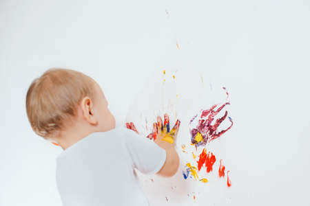 The child got dirty colors, draws on the wallの写真素材
