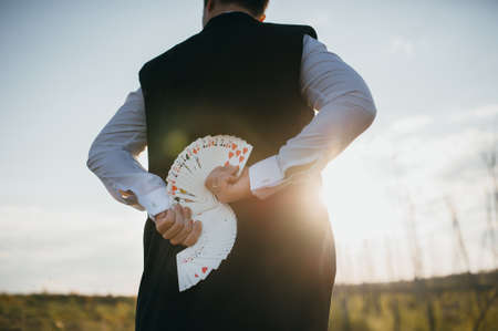 magician in a suit with cards at sunsetの写真素材