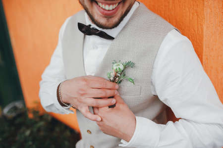 groom bow tie and waistcoat holding boutonniereの写真素材