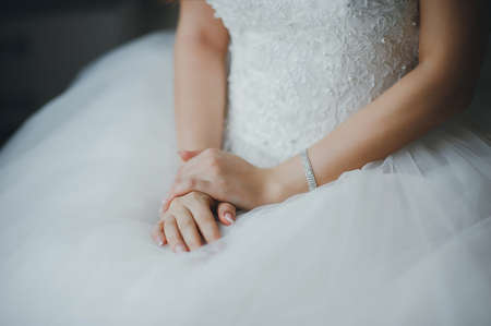 Fees bride. Bride in wedding dress sits on a chair. Hands close-upの写真素材