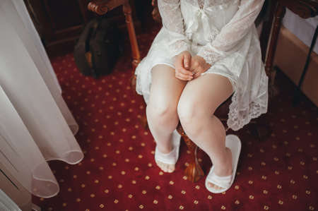 Fees bride. Bride in wedding dress sits on a chair. Hands close-upの写真素材