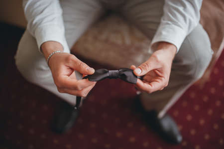 Groom is holding a brown bow-tie hdの写真素材