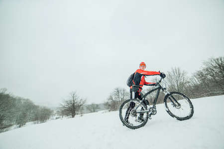 Extreme cyclist rides in the winter snowy forestの写真素材