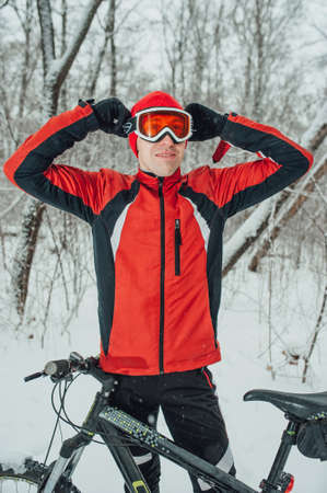 cyclist in a red outfit in the winter snowy forestの写真素材