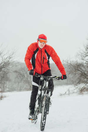Extreme cyclist rides in the winter snowy forestの写真素材