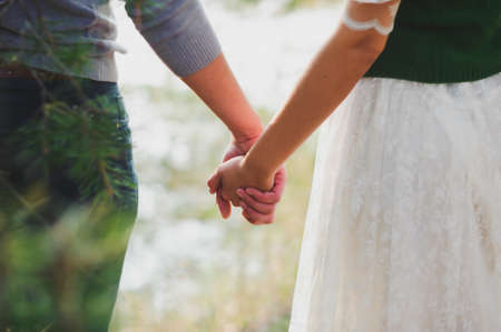 Stylish man and woman holding hands on the sunset backgroundの写真素材