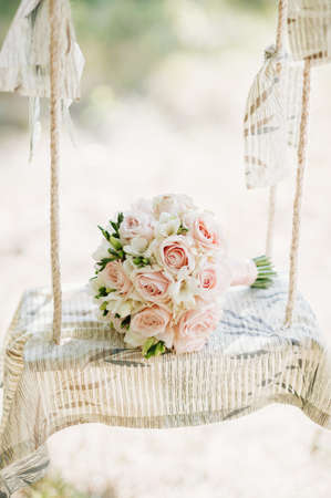 Wedding bouquet of roses lying on a white bench swingの写真素材