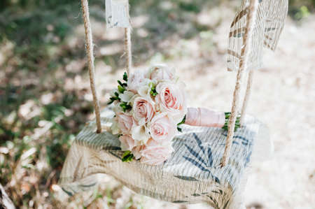 Wedding bouquet of roses lying on a white bench swingの写真素材