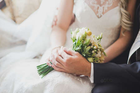groom holds his brides hand on a background of lakeの写真素材